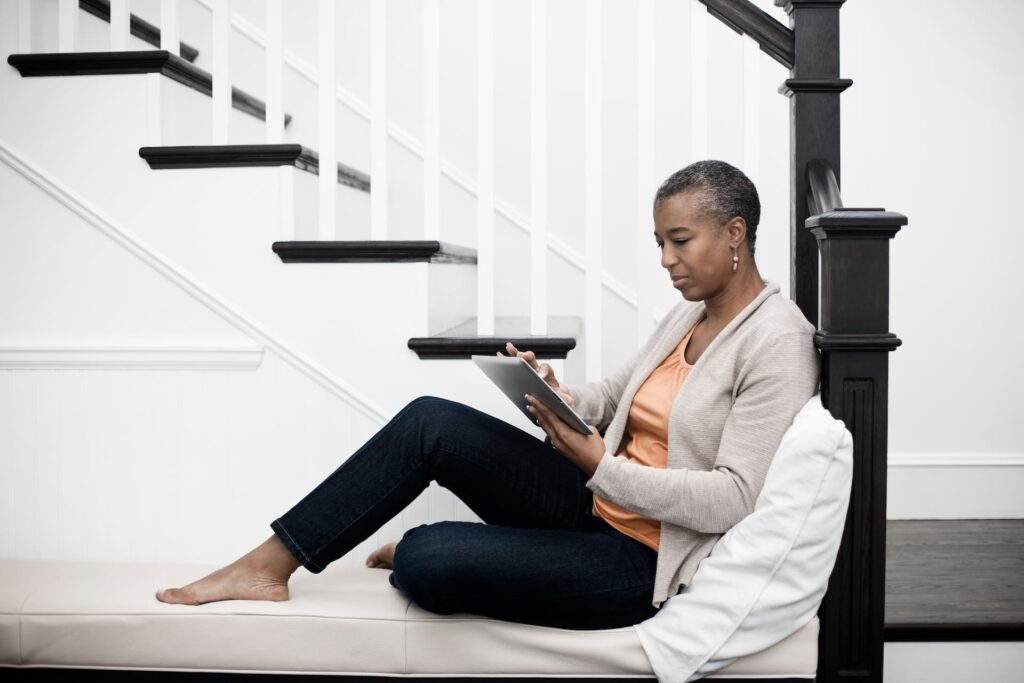 a mature woman seated in a hallway using a digital
